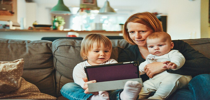 woman wth kids on her knee looking at a tablet